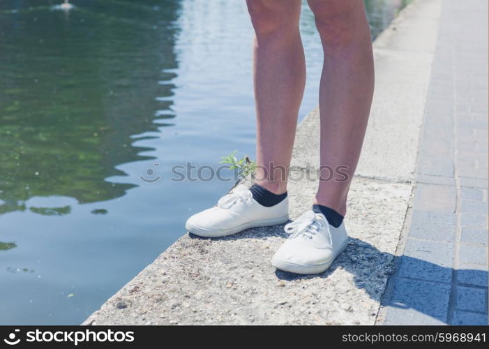 The bare legs of a young woman standing by a canal
