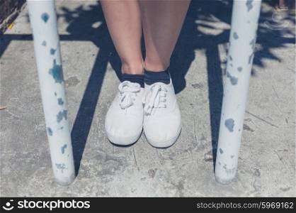 The bare legs of a young woman standing by some bars outside