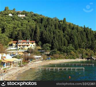 The beach at Agni, north-east Corfu, with its jetties for visiting boat trippers and the usual cluster of seafront tavernas and houses.