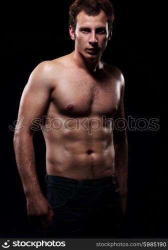 The beautiful and strong young guy. Photoshoot in a studio, dark background.