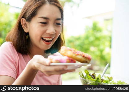 The beautiful Asian healthy middle aged woman is happy to eat donuts Because have not eaten for a long time because it is hoping for health. Concept of health care and nutritious food