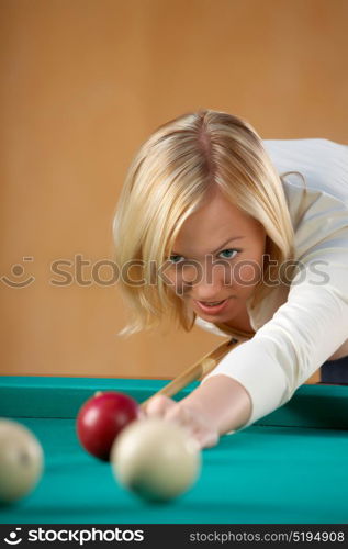 The beautiful blonde aims in a billiard sphere. Billiards