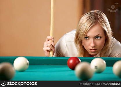 The beautiful blonde aims in the course of game at billiards