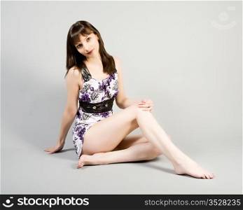 The beautiful girl in a elegant dress on a grey background