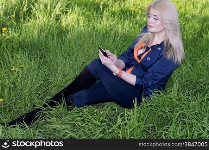 the beautiful girl on a grass with phone, a green grass