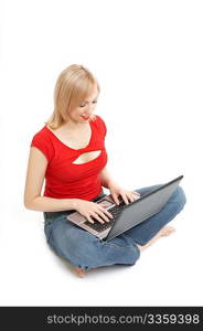 The beautiful girl sits in a cross-legged pose with a portable computer on a white background