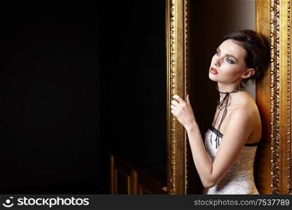 The beautiful girl with a make-up at a gold door