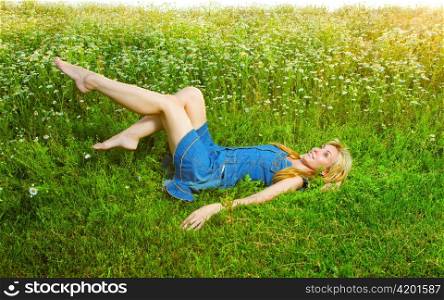 The beautiful happy girl lies in the field of camomiles