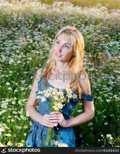 The beautiful happy young woman in the field of camomiles