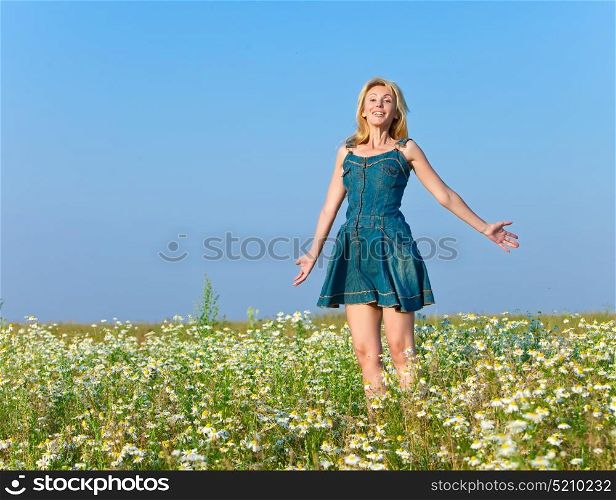 The beautiful happy young woman in the field of chamomiles