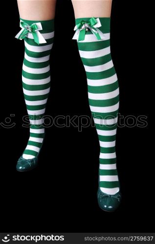 The beautiful legs of a woman in green and white stripes, with greenheels for black background.