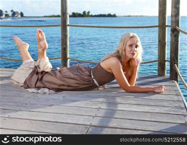 The beautiful woman lies on a wooden platform over the sea