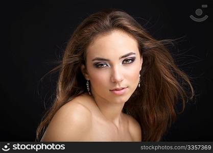 The beautiful woman with a flying hair on a black background