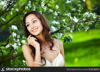 The beautiful young girl against a blossoming tree