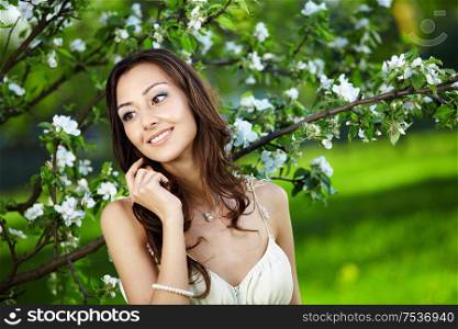 The beautiful young girl against a blossoming tree