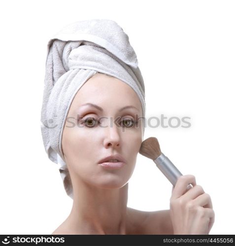 The beautiful young woman in towel with a cosmetic brush