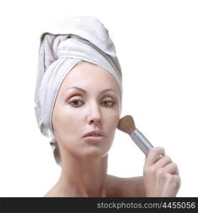 The beautiful young woman in towel with a cosmetic brush