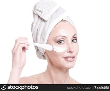 The beautiful young woman in towel with a cosmetic cream