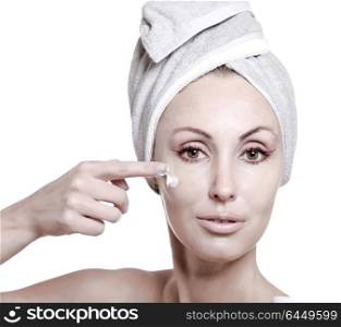 The beautiful young woman in towel with a cosmetic cream