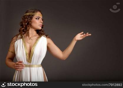 The Beautiful Young Woman Wearing White and Gold Greek Costume, Looking to Something on her Left on the Dark Background