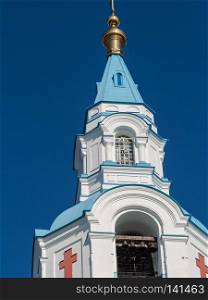 The bell tower of the Cathedral with a blue dome among tree crowns