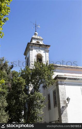 The bell tower with clock and weather vane of the Sanctuary of Our Lady of the Rock, built in the 19th century, in Queijas, Portugal