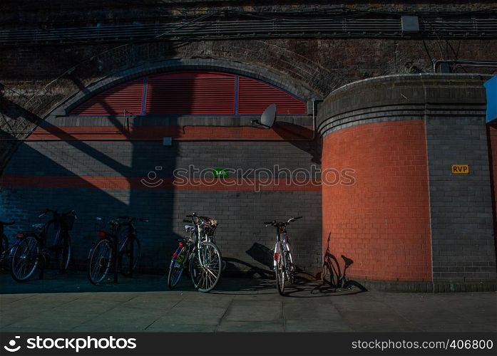 The bicycle is parked at the station in front of the concrete wall in London.