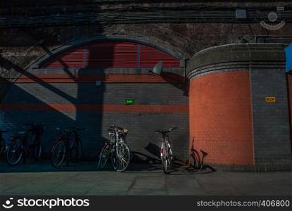 The bicycle is parked at the station in front of the concrete wall in London.