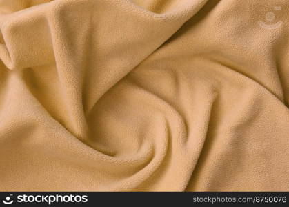 The blanket of furry orange fleece fabric. A background of light orange soft plush fleece material with a lot of relief folds