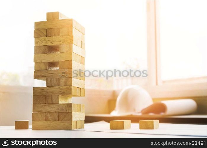 the blocks wood tower game with architectural engineer plans or blue prints compasses ,pencils and ruler on wooden table, plan and building concept.