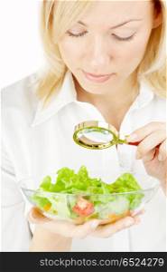 The blonde examining in a magnifier a plate with salad. Searching in food