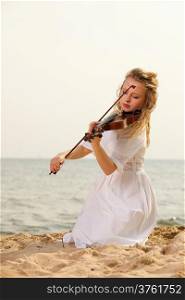 The blonde girl music lover on beach playing the violin. Love of music concept.