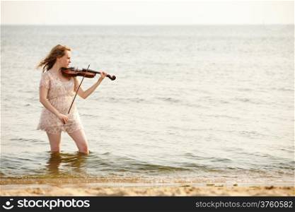 The blonde girl music lover on beach with a violin. Love of music concept.