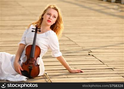 The blonde girl music lover on pier with a violin. Love of music concept.