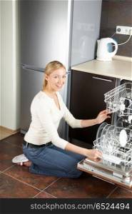 The blonde sits near to the open dishwasher on kitchen. The housewife