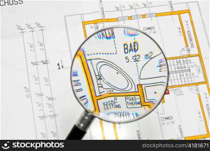the blueprint of a house viewed through a magnifying glass