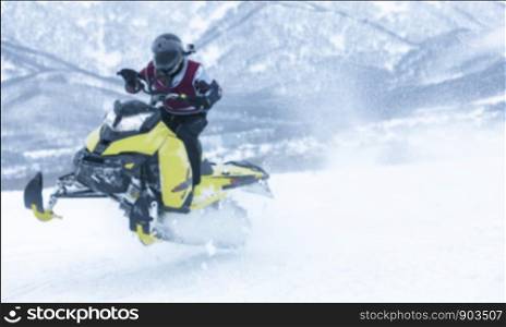 the blure background of man is flying on a snowmobile