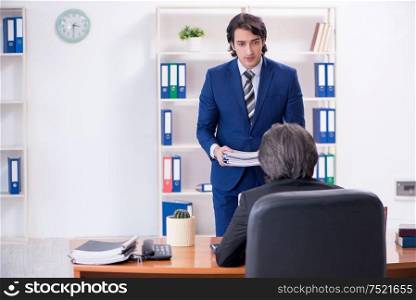 The boss and his male assistant working in the office. Boss and his male assistant working in the office