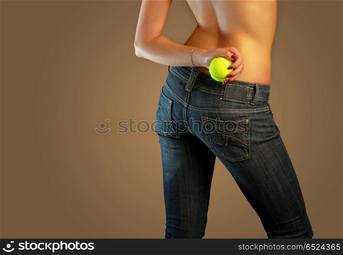 The bottom part of a body of the girl in jeans holding a tennis ball. Jeans imaginations (tennis)