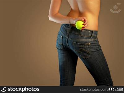 The bottom part of a body of the girl in jeans holding a tennis ball. Jeans imaginations (tennis)