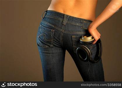 The bottom part of a body of the girl in jeans holding the headphones