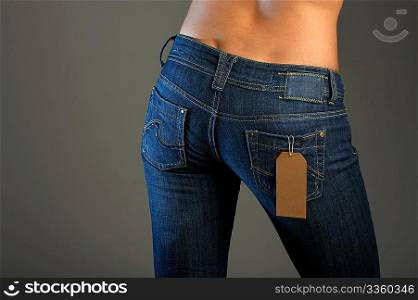 The bottom part of a body of the girl in jeans with the label in a pocket