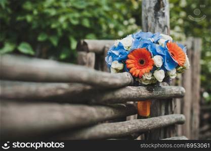 The bouquet from flowers lies on a wattled fence.