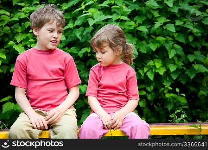 The boy and the girl sit on a bench in park