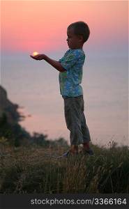 The boy holds the sun in hands