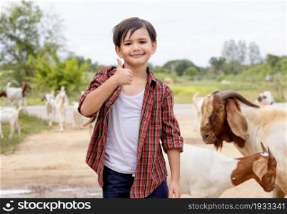The boy lives in the countryside by raising goats.