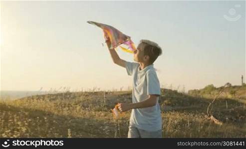 The boy runs and tries to launch a kite in the sky in a strong wind.