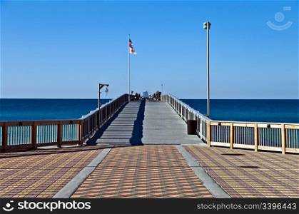 The brick entrance to a long wooden fishing pier in Florida.