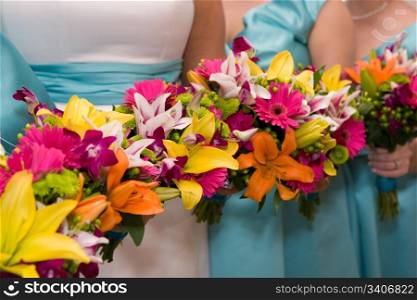 The bride and bridesmaids hold their colorful bridal flowers in a row.