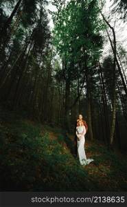 The bride and groom go through the forest hand in hand. Happy bride and groom holding hands and walking in forest on wedding day. The bride and groom go through the forest hand in hand. Happy bride and groom holding hands and walking in forest on wedding day.